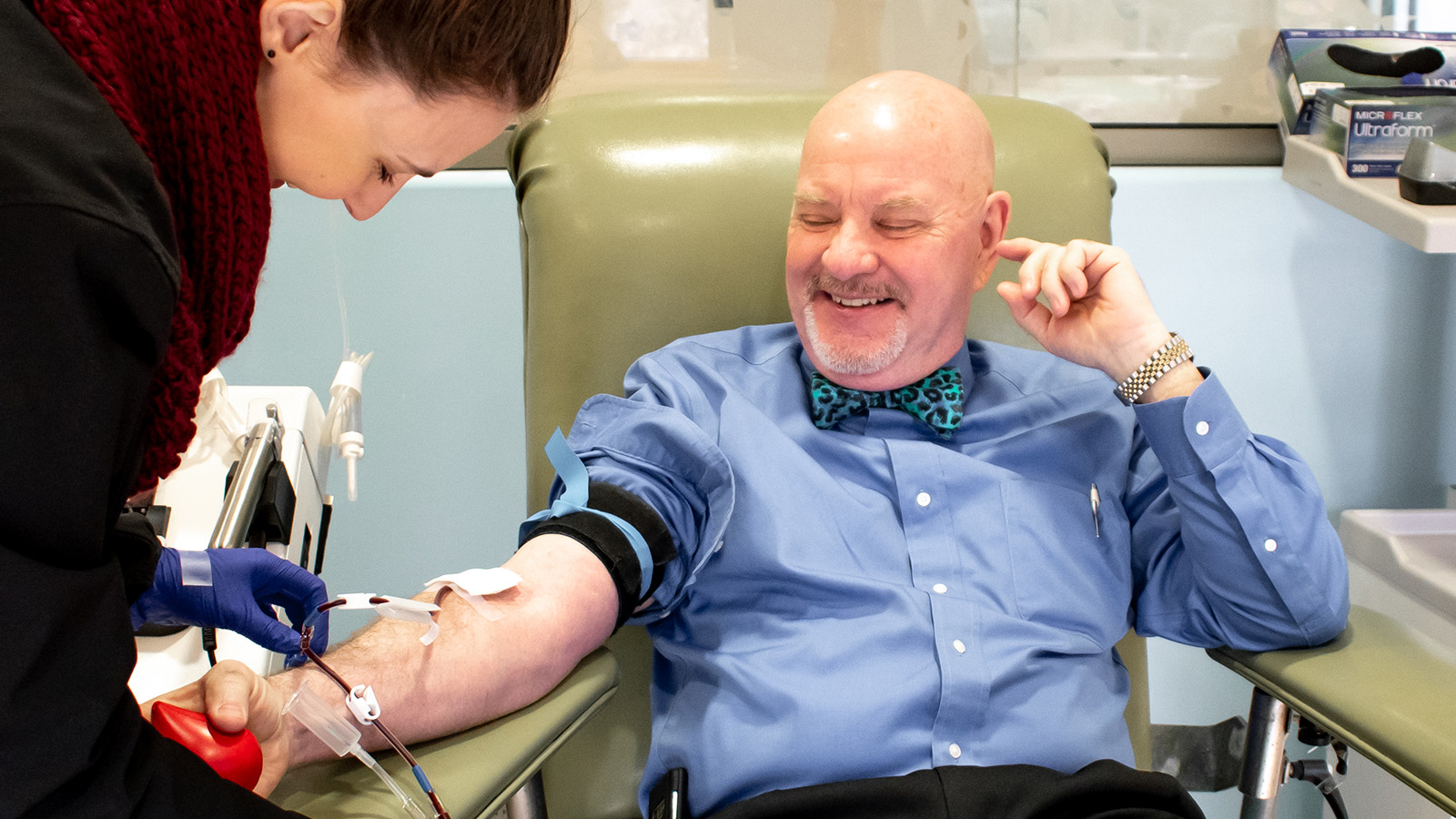 Happy donor with TBC staff giving blood